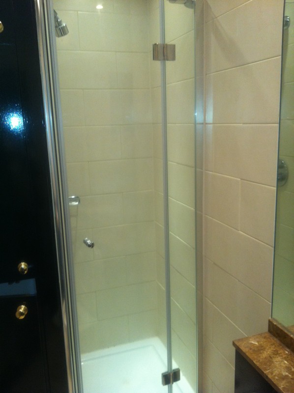 Frameless glass shower enclosure with chrome fittings in Raynes Park