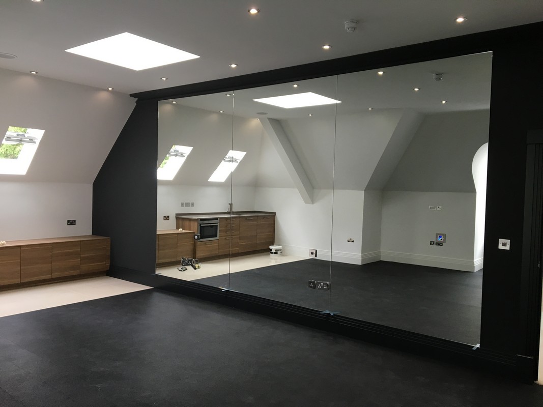 Frameless glass wall dividing loft conversion in Raynes Park