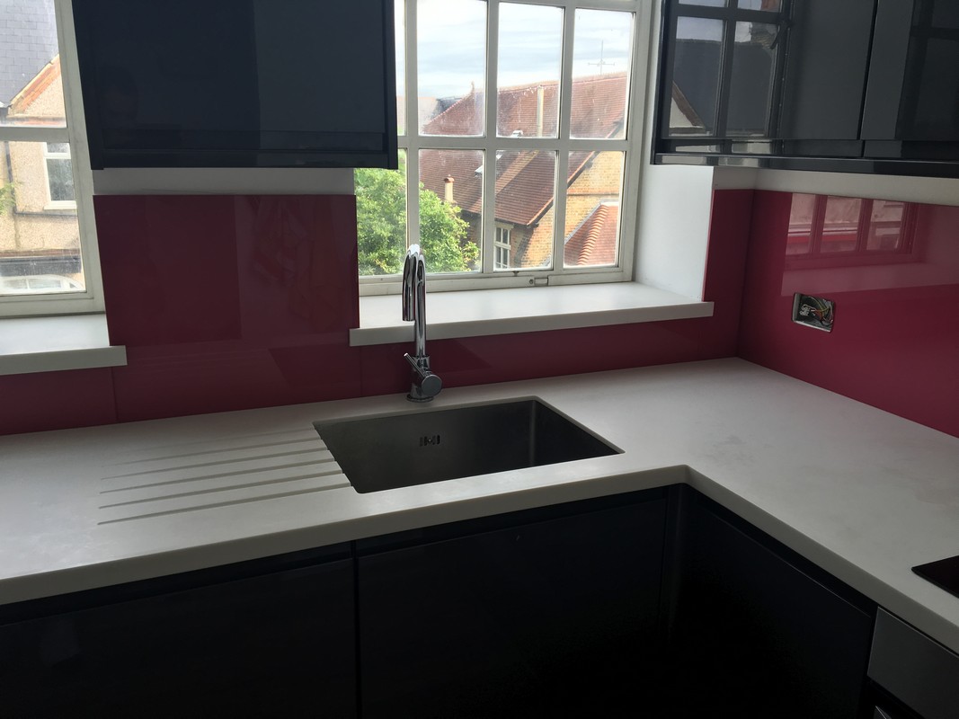 Deep plum coloured glass splashback in modern Raynes Park kitchen
